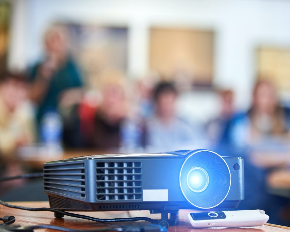 Working projector at the conference hall. Blurred people at background. Working projector at the conference hall. Blurred people at background.